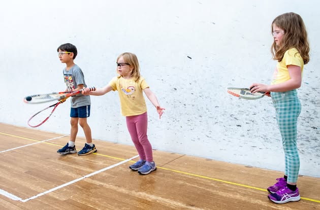 Kids learning squash basics on court