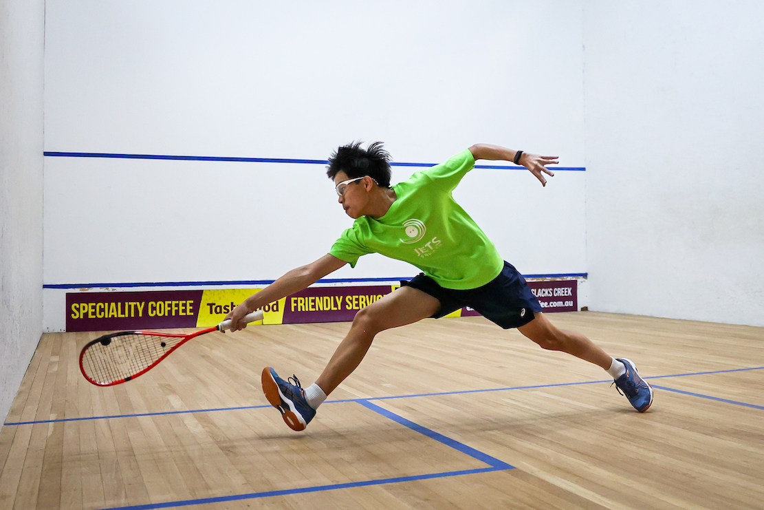 Junior player lunging for the ball on court