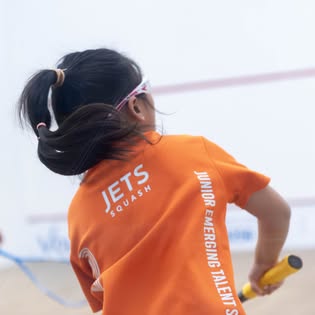 Young player wearing JETS Squash shirt on court